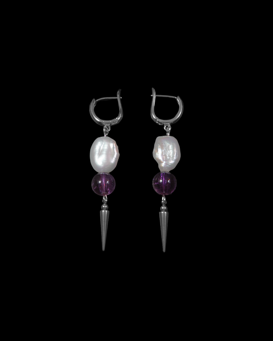 Pair of earrings with pearl and purple bead drops on a black background